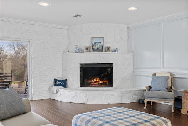 living room featuring ornamental molding, wood finished floors, visible vents, and a premium fireplace