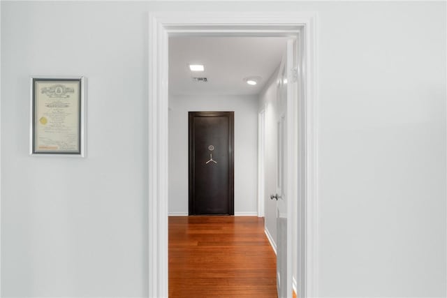 hall featuring visible vents, wood finished floors, and baseboards