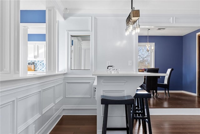 kitchen with visible vents, a notable chandelier, dark wood-style floors, a decorative wall, and hanging light fixtures