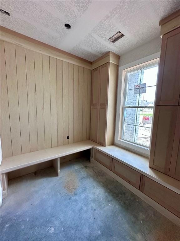 mudroom featuring a textured ceiling, a sauna, concrete floors, and wooden walls