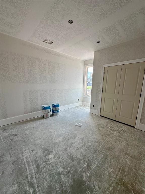 empty room featuring a textured ceiling and baseboards