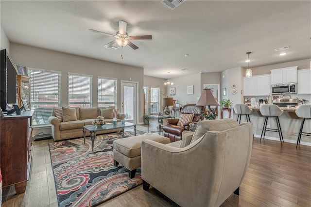 living room featuring hardwood / wood-style floors and ceiling fan with notable chandelier