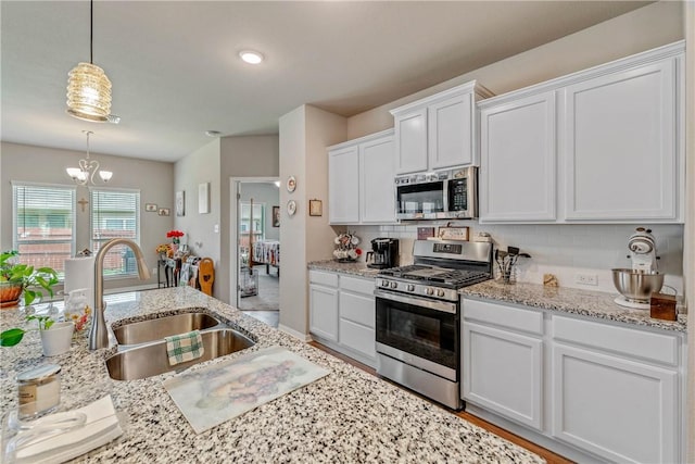 kitchen with pendant lighting, an inviting chandelier, white cabinets, sink, and stainless steel appliances