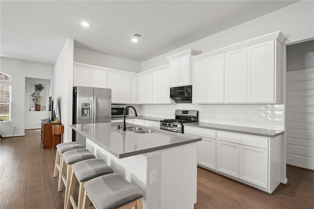 kitchen featuring a sink, backsplash, a kitchen breakfast bar, appliances with stainless steel finishes, and visible vents