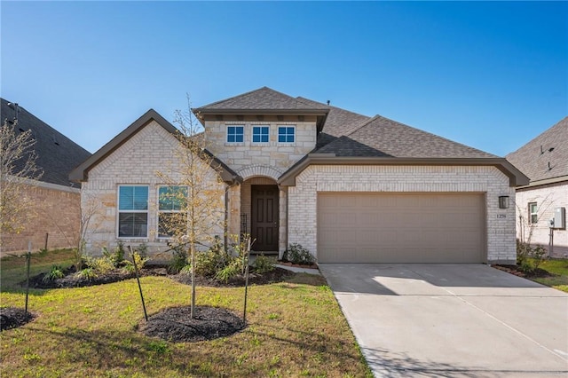 french provincial home with concrete driveway, roof with shingles, stone siding, a front lawn, and a garage