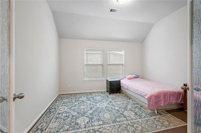 bedroom featuring baseboards, lofted ceiling, and visible vents