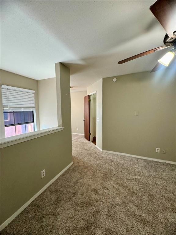 carpeted spare room featuring ceiling fan