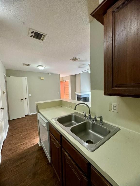 kitchen featuring dark brown cabinets, a textured ceiling, white dishwasher, sink, and dark hardwood / wood-style floors