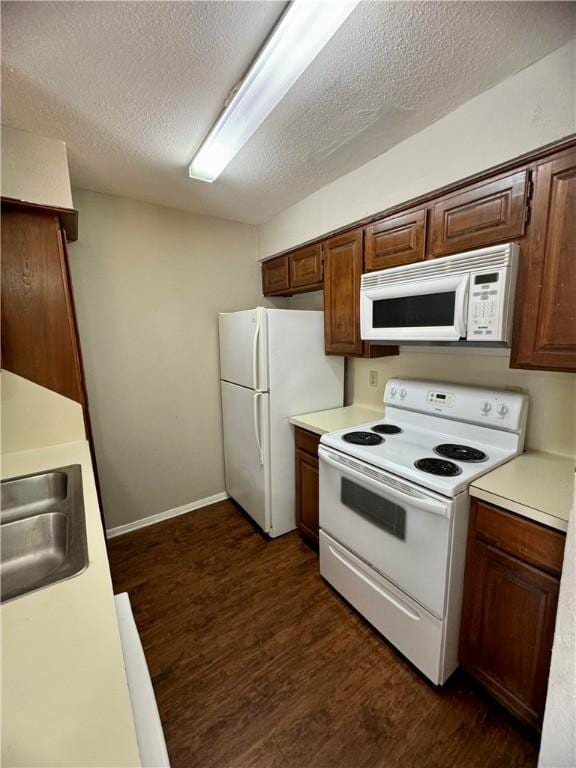 kitchen with a textured ceiling, dark hardwood / wood-style flooring, sink, and white appliances