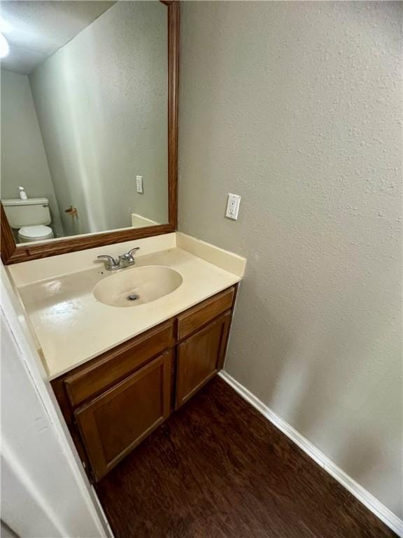 bathroom featuring vanity, wood-type flooring, and toilet