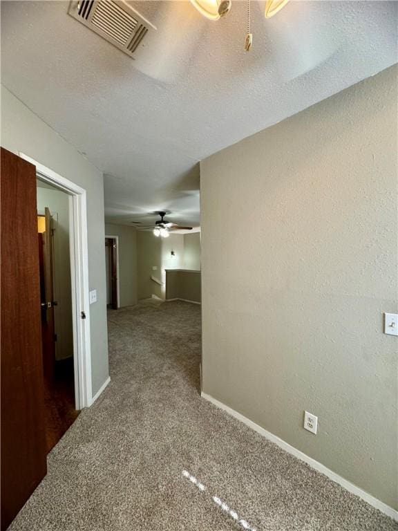 hall featuring dark carpet and a textured ceiling