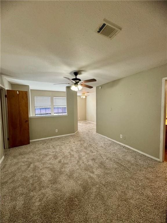 carpeted empty room featuring a textured ceiling and ceiling fan