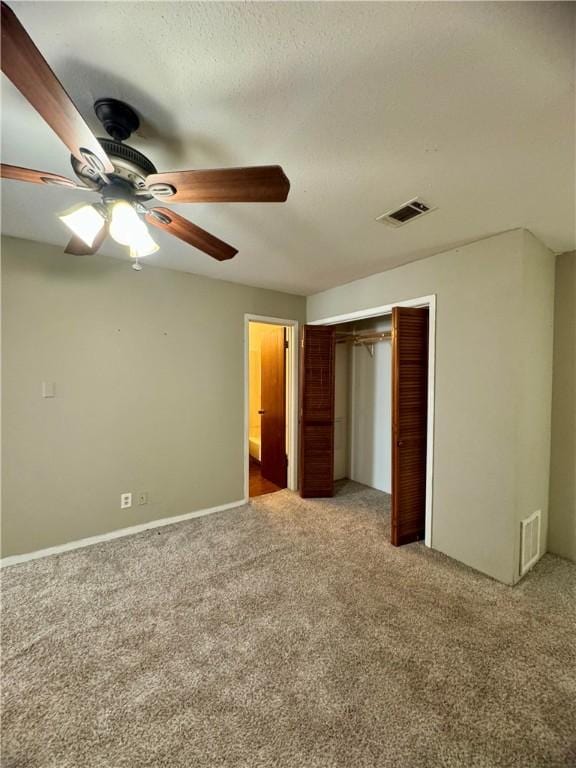 unfurnished bedroom featuring ceiling fan, ensuite bathroom, light colored carpet, a textured ceiling, and a closet