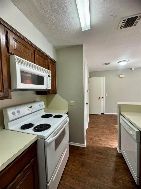 kitchen with a textured ceiling, white appliances, dark hardwood / wood-style floors, and dark brown cabinets