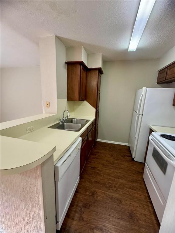 kitchen with a textured ceiling, dark hardwood / wood-style flooring, sink, and white appliances