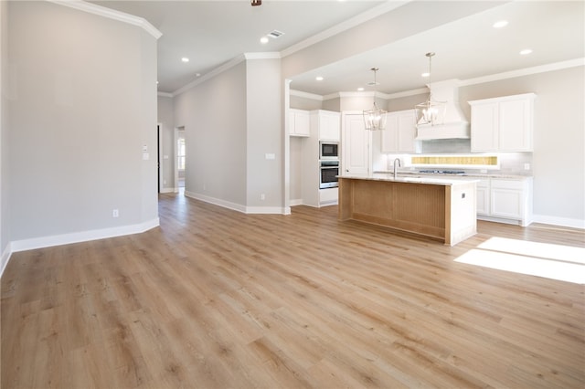 kitchen featuring custom exhaust hood, a kitchen island with sink, oven, decorative backsplash, and white cabinetry