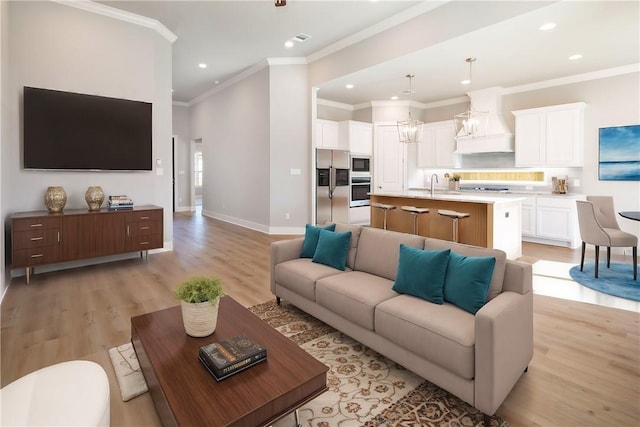 living room with light hardwood / wood-style floors, ornamental molding, and sink