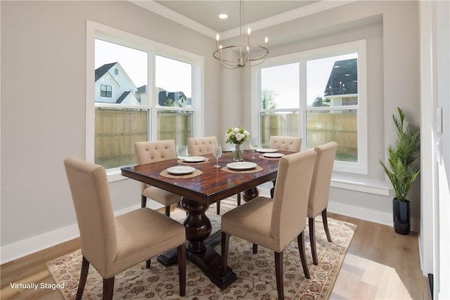 dining area with a chandelier, light wood-type flooring, plenty of natural light, and ornamental molding