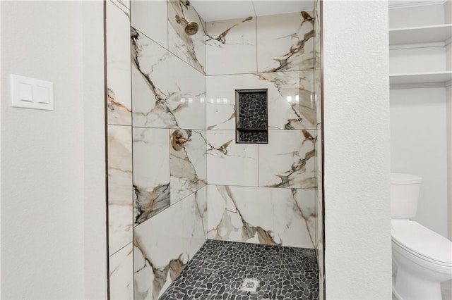 bathroom featuring toilet and a tile shower