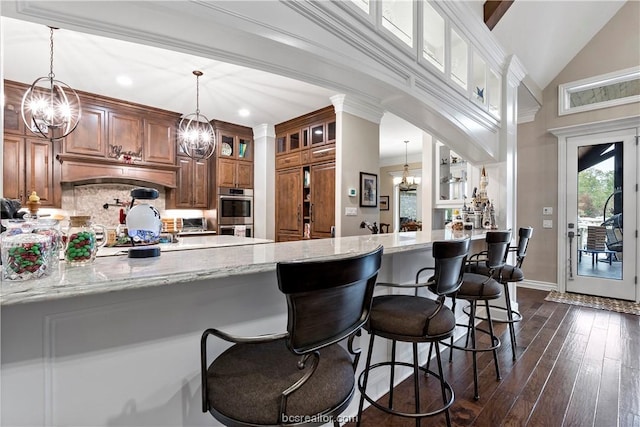 kitchen with kitchen peninsula, light stone counters, and dark wood-type flooring