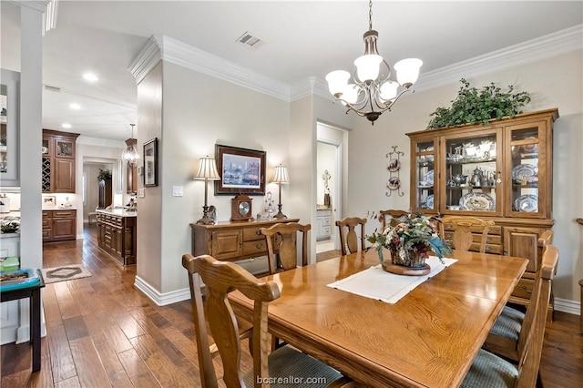 dining room with dark hardwood / wood-style flooring, crown molding, and a notable chandelier