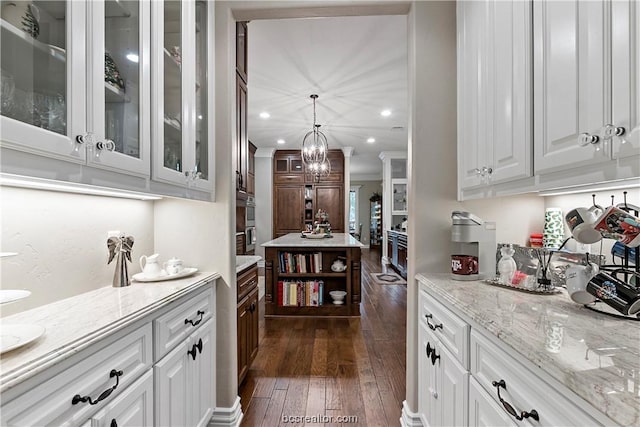 kitchen featuring light stone counters, white cabinetry, pendant lighting, and dark hardwood / wood-style floors