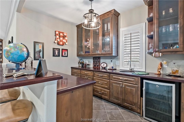 bar with sink, wine cooler, dark tile patterned floors, dark brown cabinetry, and a chandelier