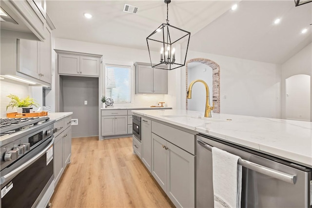 kitchen featuring tasteful backsplash, gray cabinetry, stainless steel appliances, sink, and hanging light fixtures