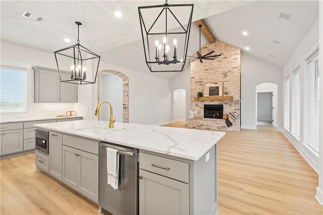 kitchen with gray cabinets, a kitchen island with sink, a fireplace, and decorative light fixtures