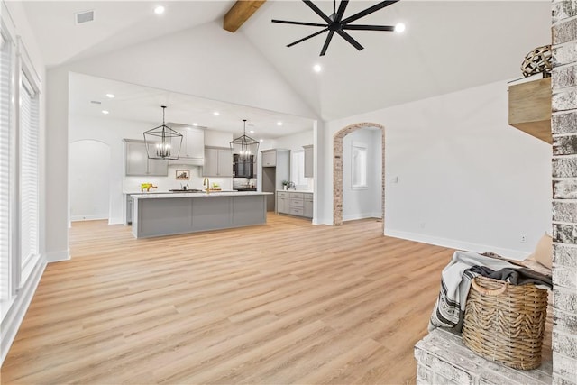 unfurnished living room with beam ceiling, ceiling fan, high vaulted ceiling, and light hardwood / wood-style floors