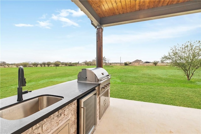 view of patio / terrace featuring a rural view, exterior kitchen, sink, and beverage cooler