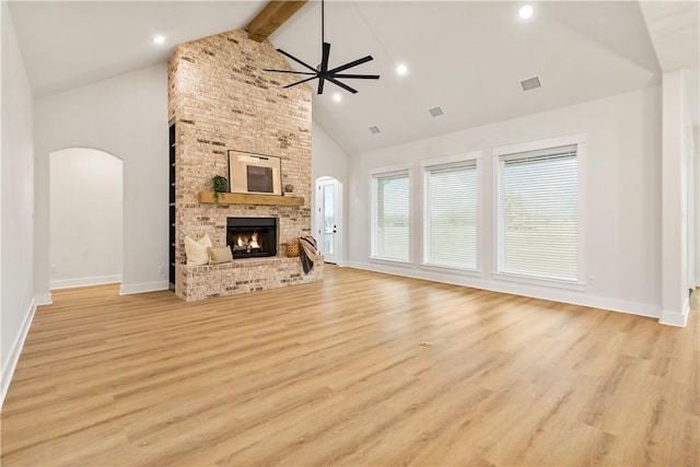 unfurnished living room with beamed ceiling, light wood-type flooring, high vaulted ceiling, and a brick fireplace