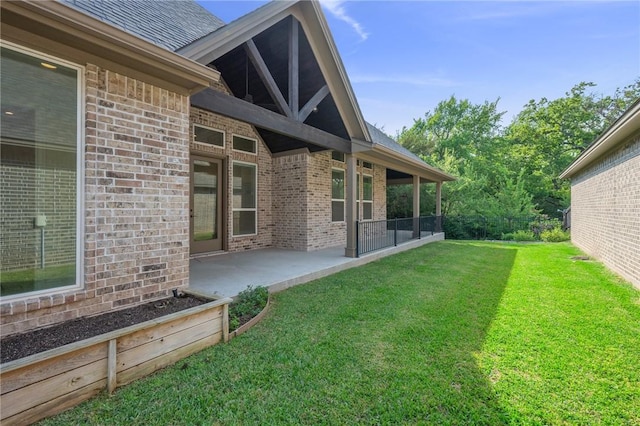 rear view of property featuring a patio, a lawn, and brick siding