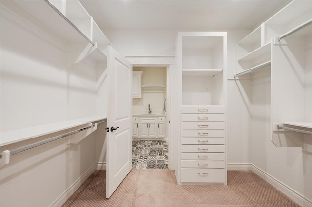 walk in closet with a sink and light carpet