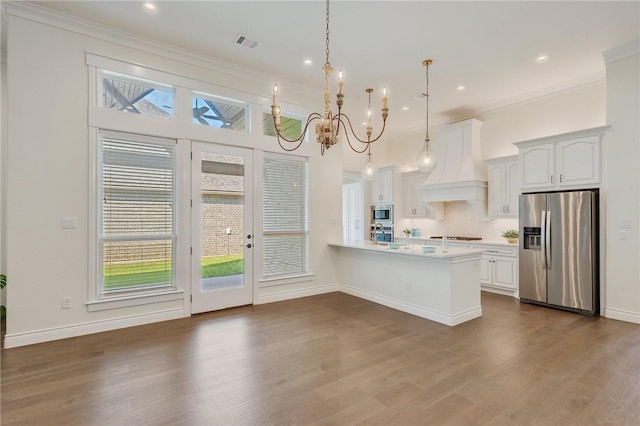 kitchen with visible vents, an inviting chandelier, premium range hood, a peninsula, and stainless steel appliances