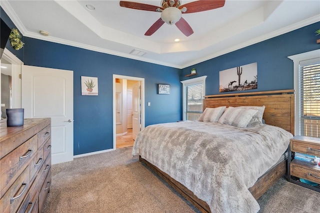 bedroom with ceiling fan, a tray ceiling, and ensuite bath