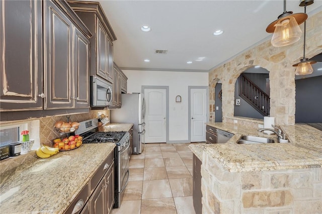 kitchen with tasteful backsplash, light stone countertops, appliances with stainless steel finishes, and pendant lighting