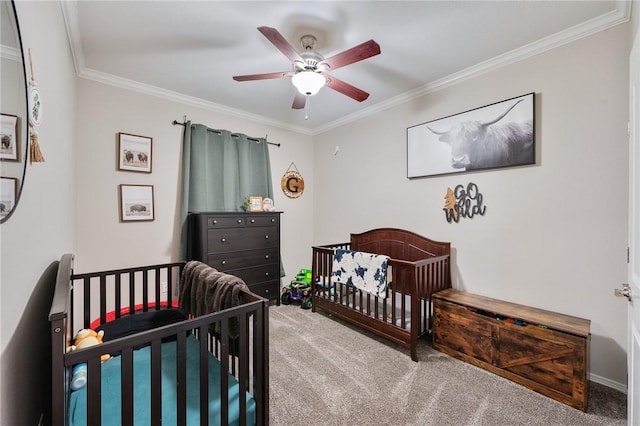 bedroom featuring a crib, ornamental molding, ceiling fan, and carpet