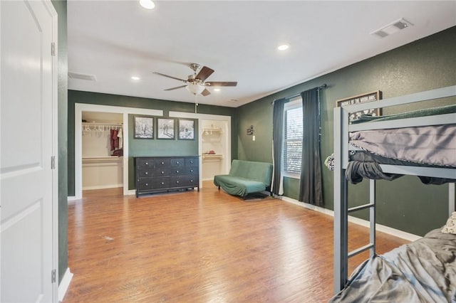 bedroom featuring wood-type flooring, a spacious closet, ceiling fan, and a closet