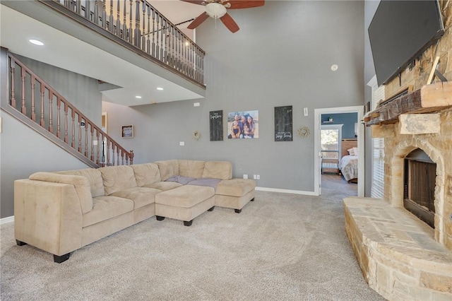 carpeted living room with a towering ceiling, a fireplace, and ceiling fan