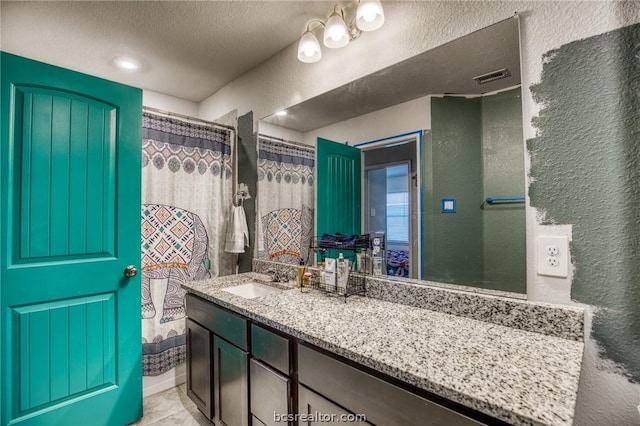 bathroom featuring tile patterned flooring, vanity, curtained shower, and a textured ceiling