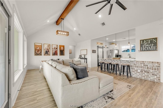 living room featuring vaulted ceiling with beams, light hardwood / wood-style flooring, ceiling fan, and sink