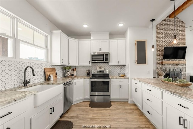 kitchen featuring decorative backsplash, light wood-type flooring, appliances with stainless steel finishes, decorative light fixtures, and white cabinetry