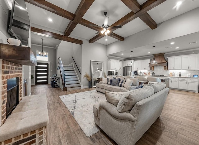 living room featuring beamed ceiling, coffered ceiling, a fireplace, and light hardwood / wood-style flooring