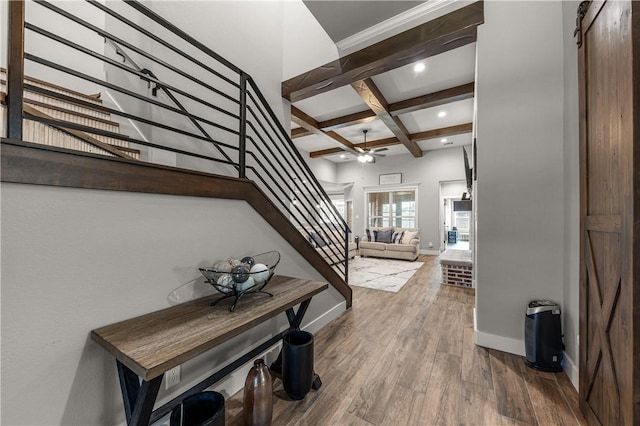 interior space featuring coffered ceiling, beam ceiling, ceiling fan, a barn door, and hardwood / wood-style floors