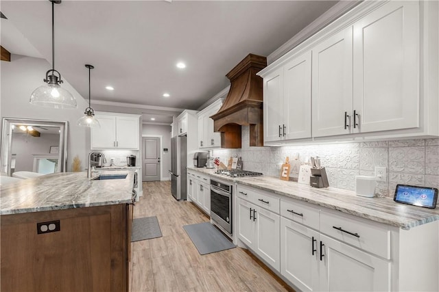 kitchen with appliances with stainless steel finishes, decorative light fixtures, sink, white cabinets, and backsplash