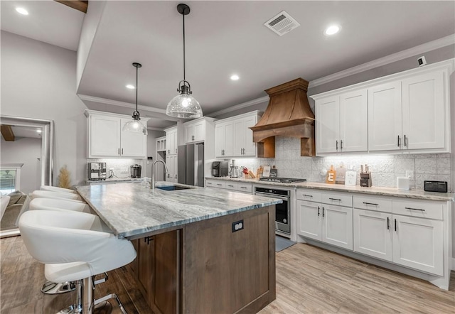 kitchen with white cabinetry, stainless steel appliances, custom exhaust hood, and pendant lighting