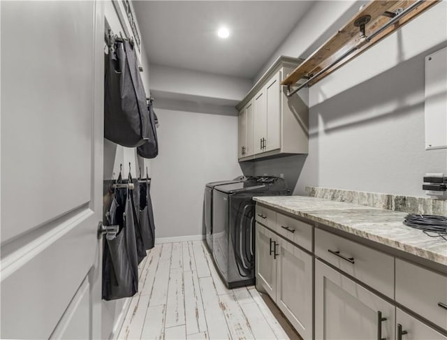 clothes washing area with washer and dryer and cabinets