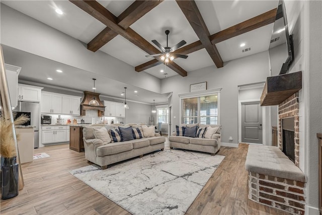 living room with ceiling fan, coffered ceiling, a fireplace, and light hardwood / wood-style flooring