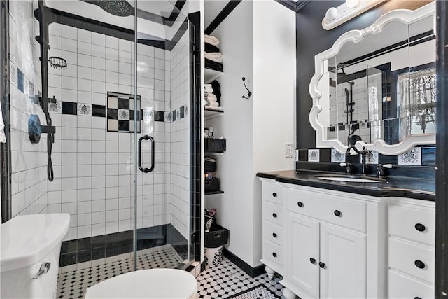 bathroom with vanity, toilet, a shower with shower door, and tile patterned flooring